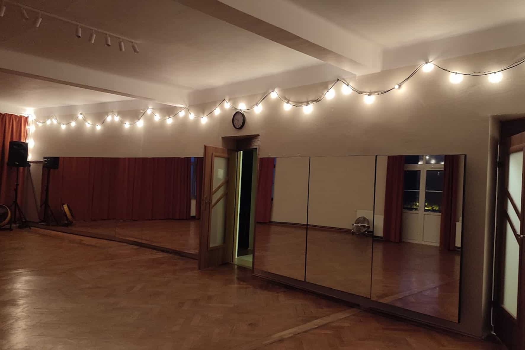 Przestronna sala do tańca z lustrami i dekoracją świetlną.