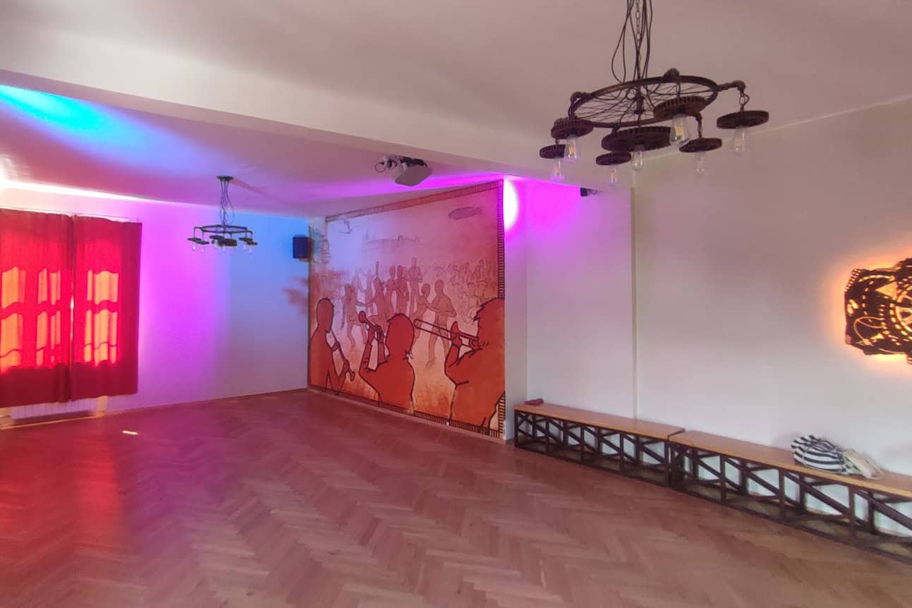 Przestronna sala taneczna KMiTa Swing z kolorowym oświetleniem i muralem na ścianie.